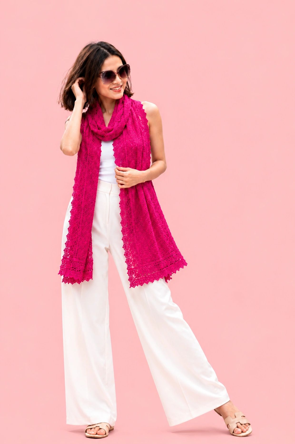 Woman wearing white pants and a vibrant pink scarf against a pink background.