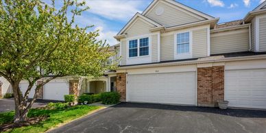 Two-story townhouse with garage and tree in front.