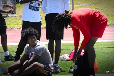 Athletes preparing and resting on a sports field during practice.