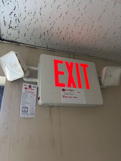 Illuminated EXIT sign with emergency lights mounted on a wall.
