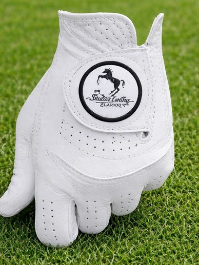 White leather golf glove with horse logo on green grass.