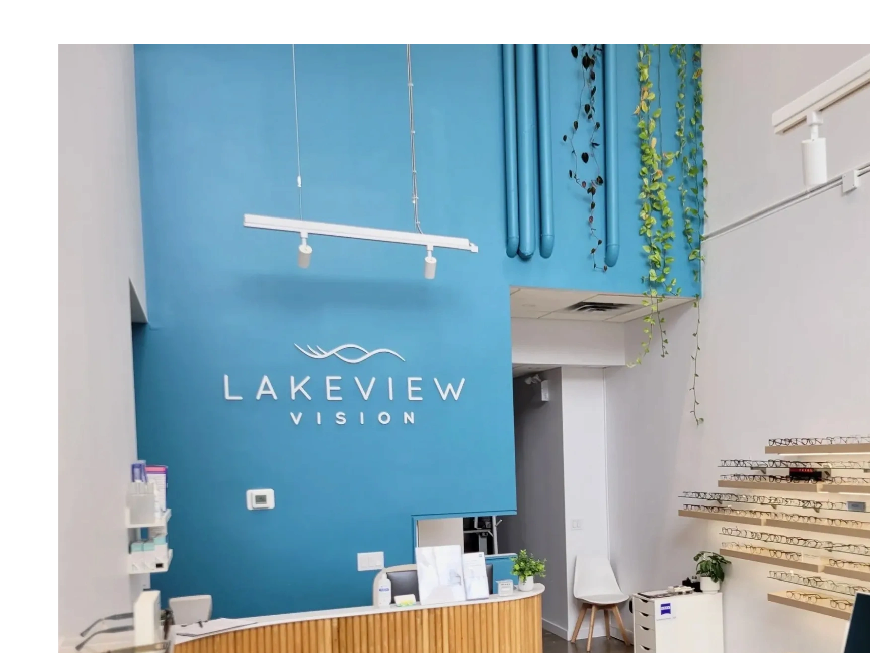 Modern eyeglasses store interior with blue accent wall and wooden displays.