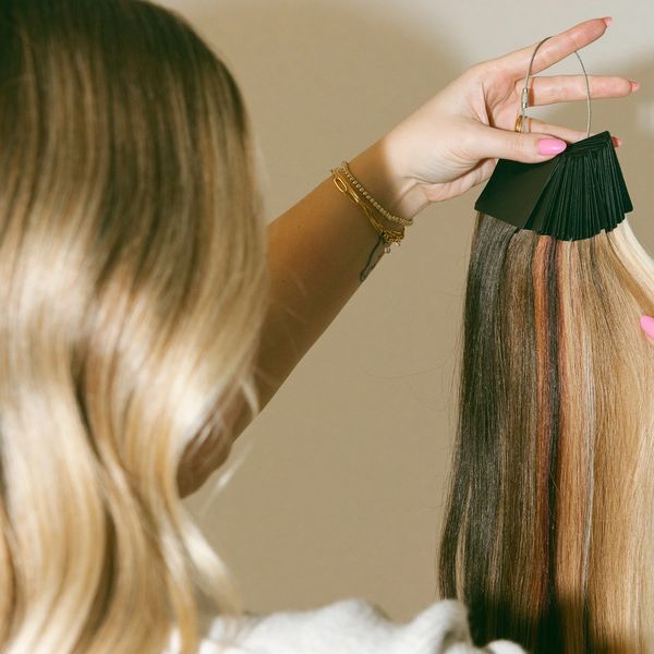 Person holding a hair color sample ring showing various hair shades.