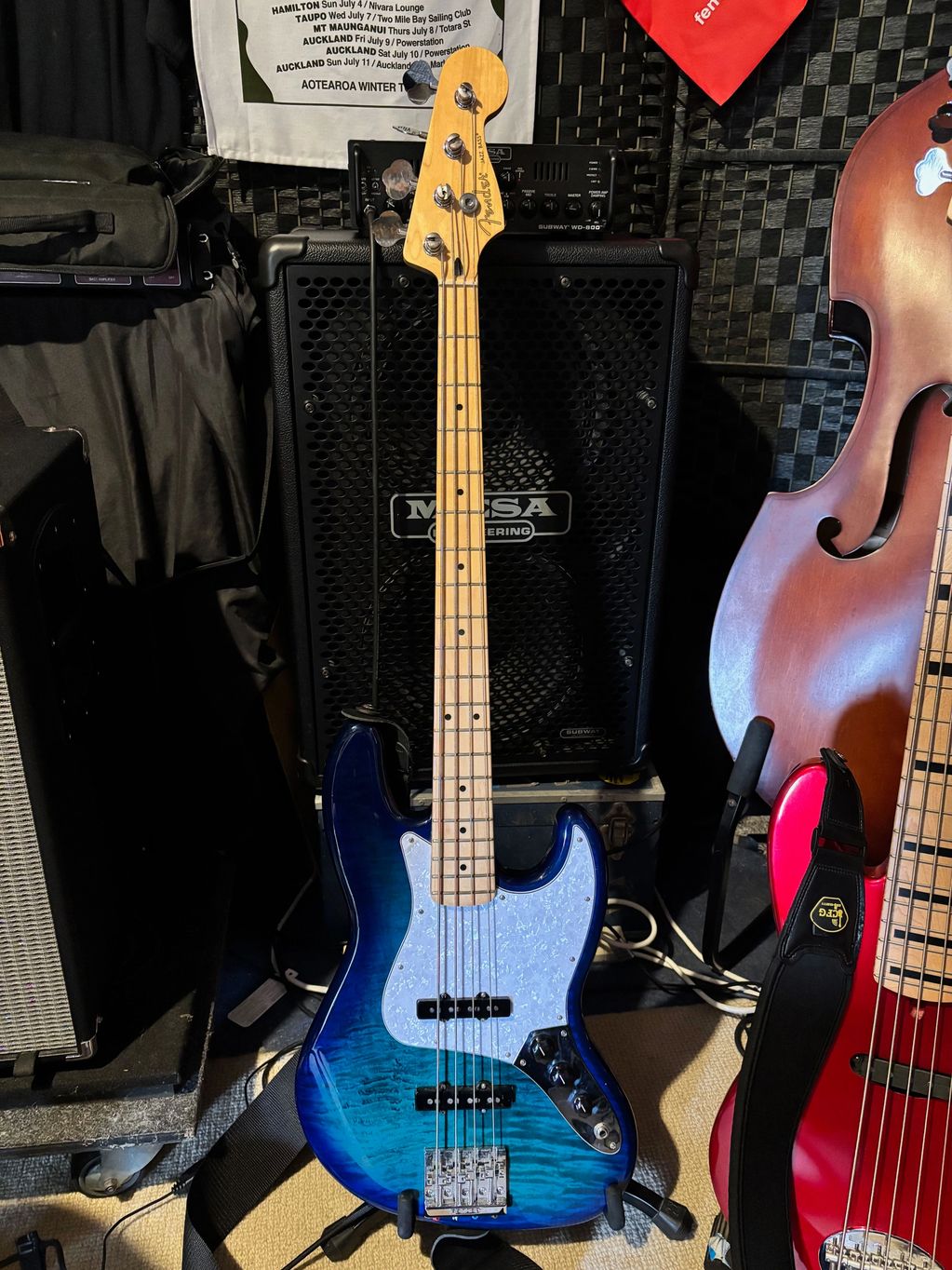 Blue Fender electric bass guitar standing in front of a MESA amplifier.