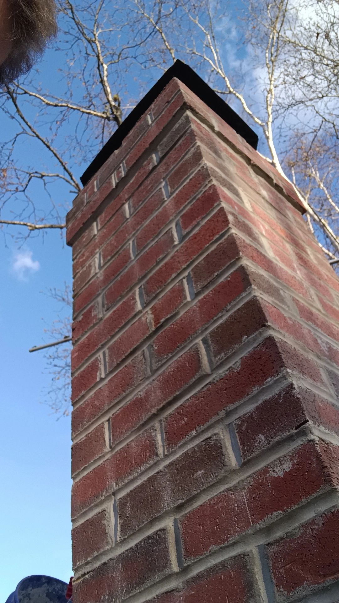 Close-up of a red brick chimney against a clear blue sky.