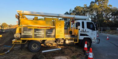 J and J Locates vacuum excavation truck providing utility locating and service verification at a construction site.