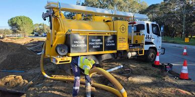 Vacuum excavation truck performing non-destructive digging and underground utility exposure at a construction site.