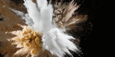Explosive burst of white and brown powder on black background.