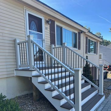 A newly built exterior staircase with black metal railings and white posts.