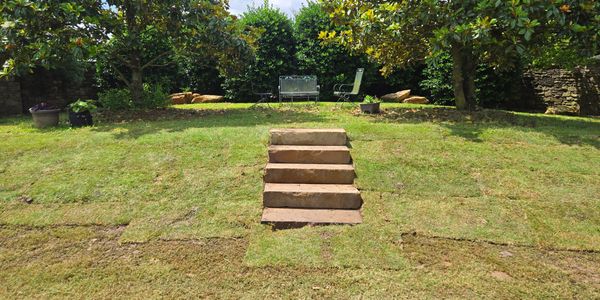 Stone steps lead up to a garden seating area surrounded by greenery.