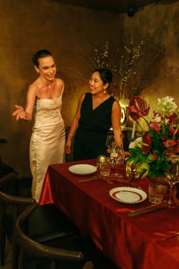 Two women chatting by a decorated dinner table.