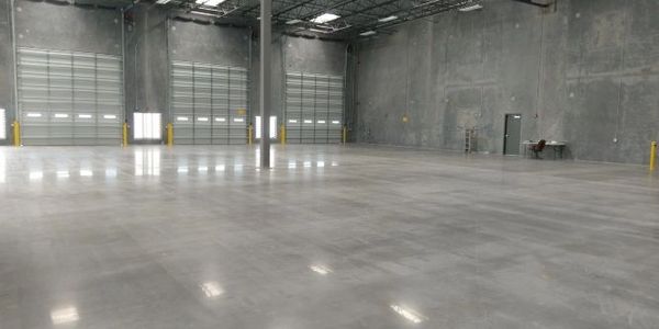 Spacious empty industrial warehouse with concrete floors and multiple loading bay doors.