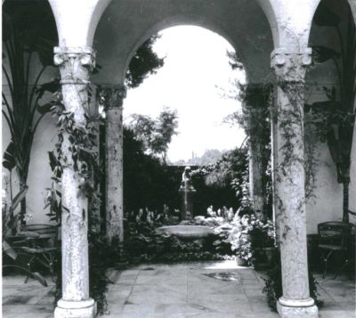 Garden view through stone arches with fountain.