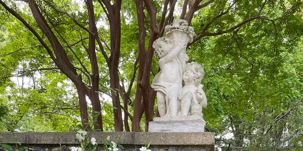 Stone statue of two children under a tree.