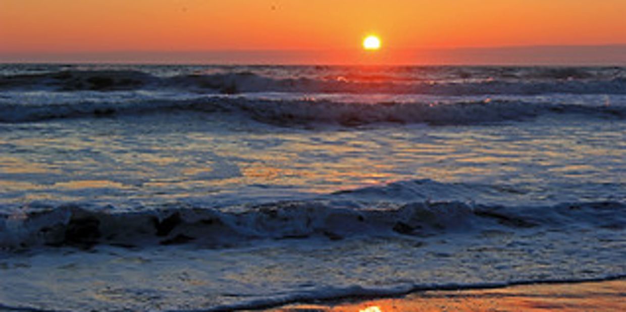 Beautiful sunrise over turbulent white capped ocean waves in Virginia Beach.