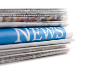 Stack of newspapers with one prominently showing the word NEWS.
