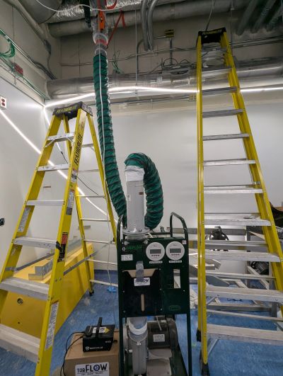 Industrial equipment setup with two yellow ladders and ventilation duct.