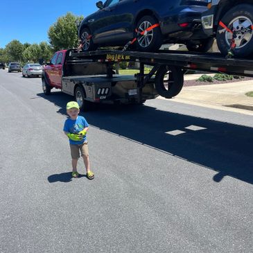 Young boy wearing gloves working with father transporting cars