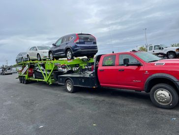 Red Dodge 5500 Hotshot Truck with 2021 Big Tex Green Car Hauler loaded transporting cars 