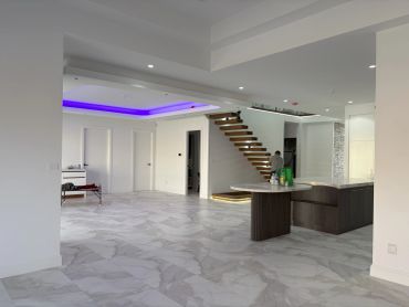 Modern spacious interior with floating wooden stairs and purple lighting.
