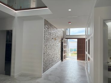 Bright modern hallway with textured stone wall and open wooden door.