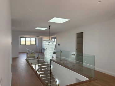 Modern indoor staircase with glass railing and wooden floors.