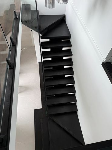 Modern black staircase with glass railing.