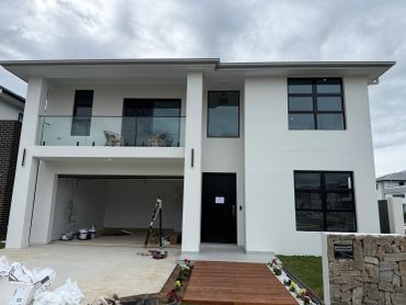 Modern two-story white house with large windows.