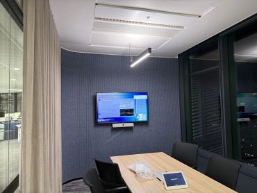 Modern small conference room with screen and tech setup.