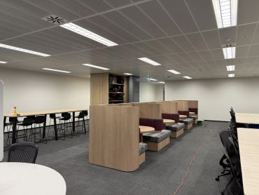 Modern office workspace with booths and high tables.