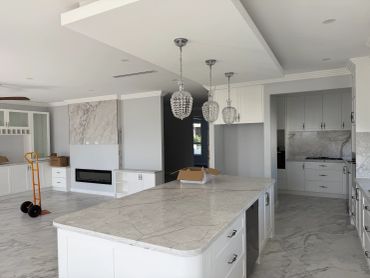 Modern kitchen with marble countertops and white cabinetry.