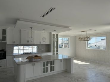 Modern white kitchen with marble countertops and an island.