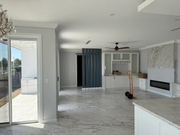 Spacious modern living room with marble floors and fireplace.
