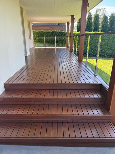 Wooden deck with stairs and metal railing on a porch.