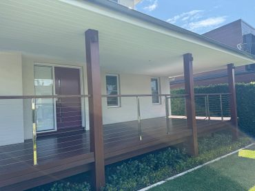 Modern wooden porch with metal railing.