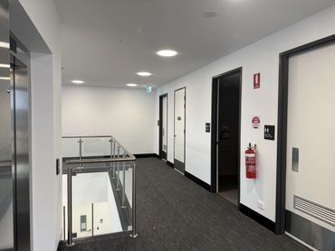 Modern office corridor with doors and elevators.