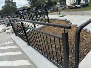 Black metal ramps and railings with steps and mulch bed.
