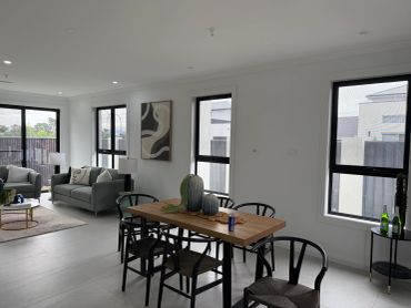Modern dining and living room with wooden table and gray sofas.