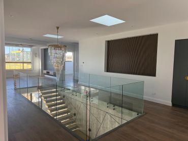 Modern interior with glass staircase railing and skylight.