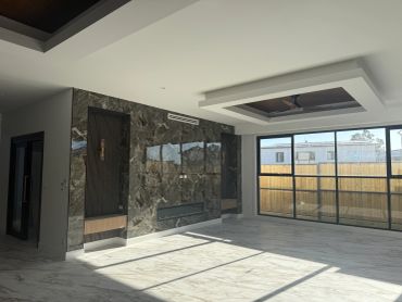 Bright modern living room with large windows and marble accent wall.