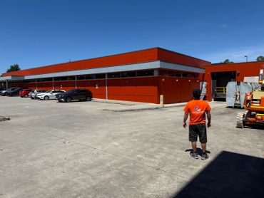 Man walking near a red warehouse on a sunny day.