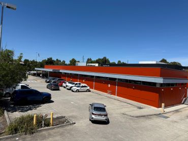 Parking lot with cars outside a red building on a clear day.
