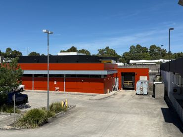Modern red and black warehouse building on a sunny day.