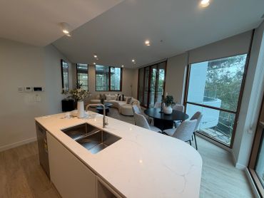 Modern open-concept kitchen and living area with large windows.