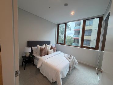 Neat bedroom with large windows and decorative pillows.