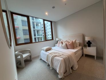 Minimalist bedroom with neutral tones and large windows.