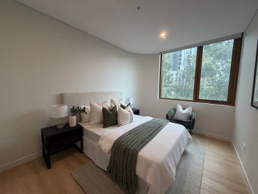 Modern bedroom with neutral tones and a large window.