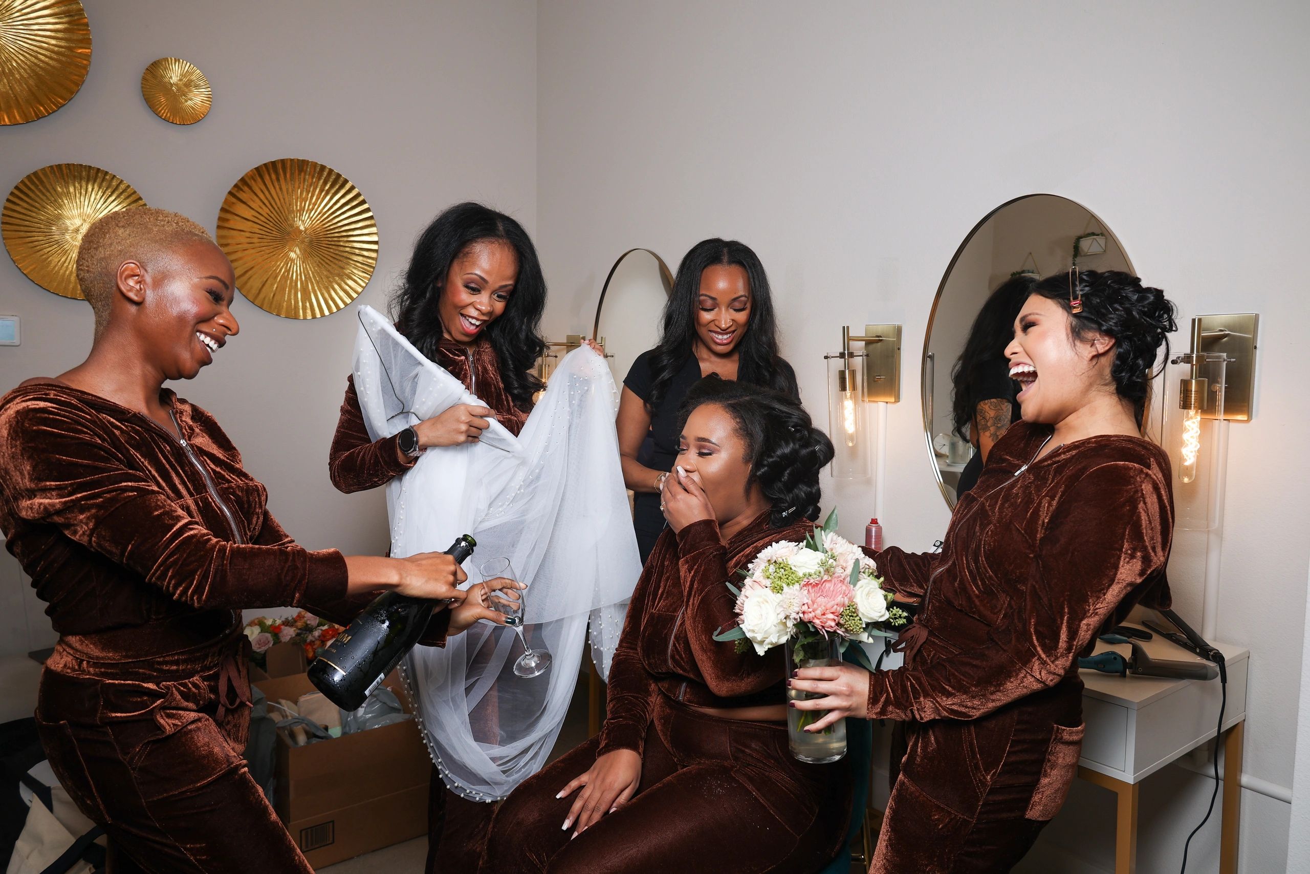 Women celebrating, laughing, and pouring champagne indoors.