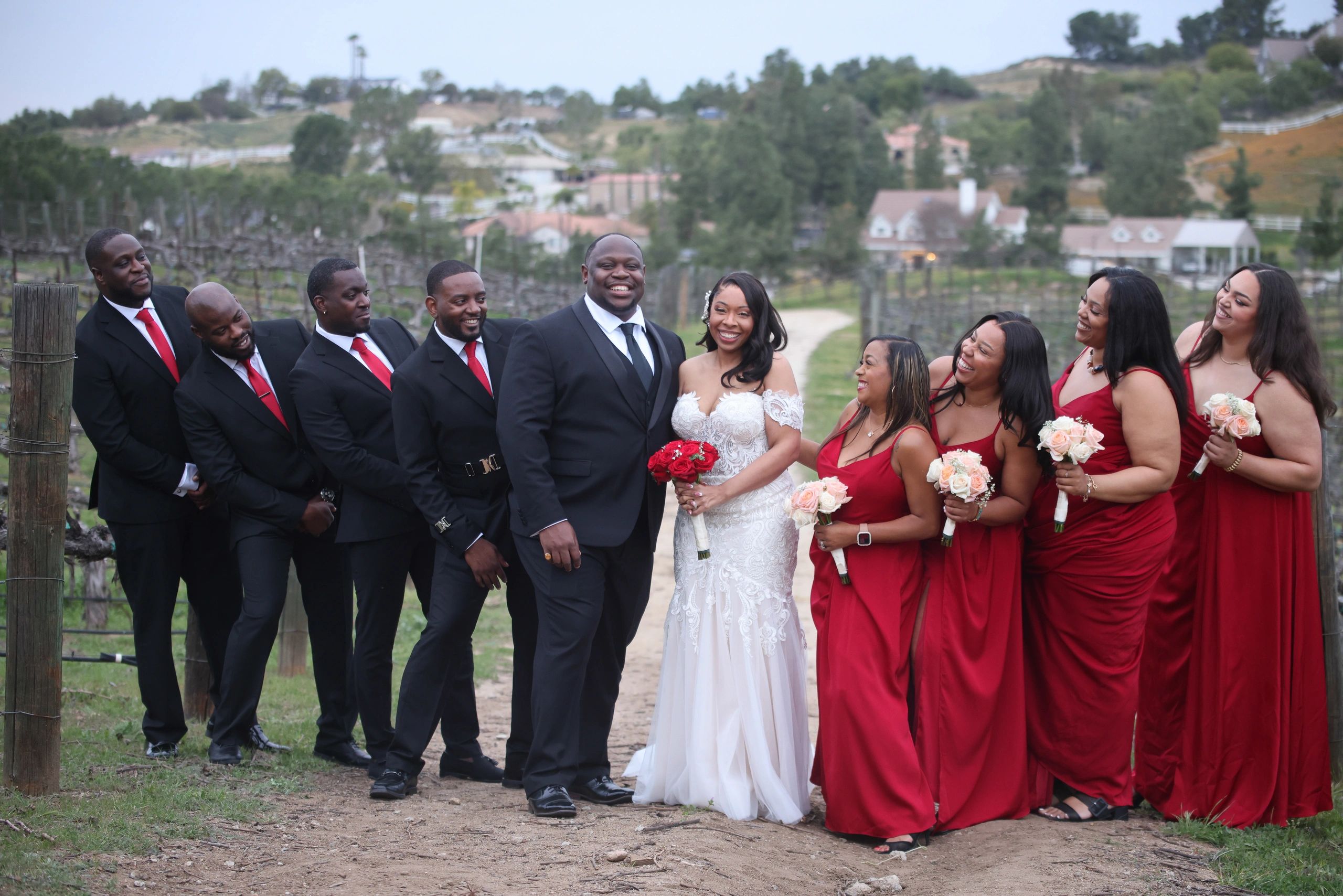 Happy wedding party posing outdoors with groom and bride.