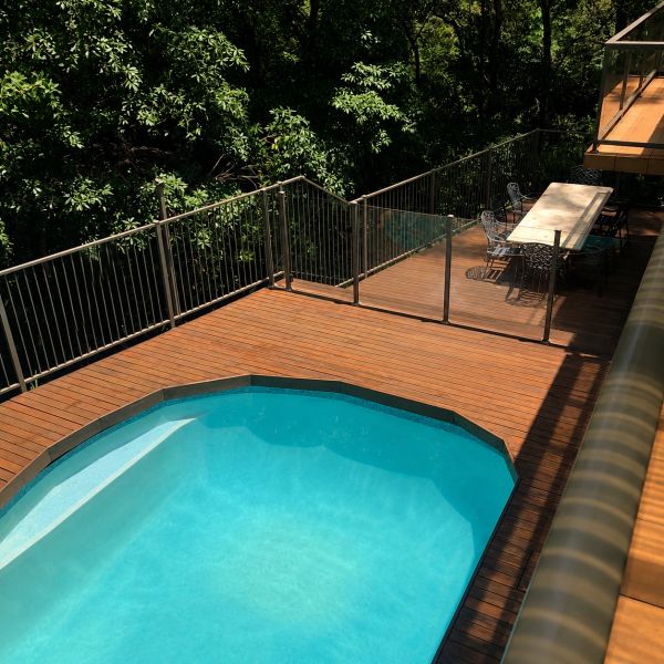 A serene backyard pool with wooden deck and outdoor dining area.